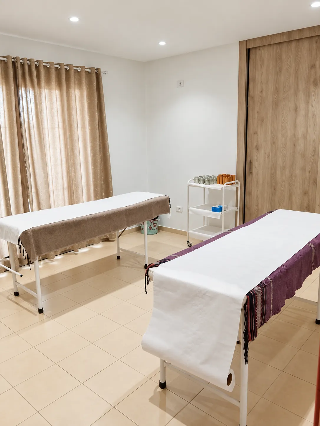 Salle de soins Relaxeo avec deux tables de massage, rideaux lin et placard en bois